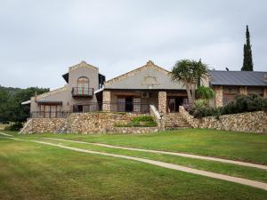 a house with a stone wall and a grass yard at Swartklip Game Lodge in Riversdale