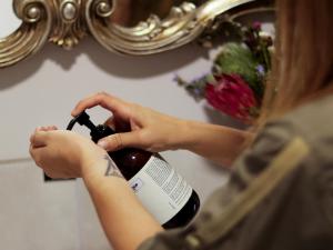 a woman is opening a bottle of wine in front of a mirror at Swartklip Game Lodge in Riversdale