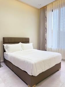 a bedroom with a bed with white sheets and a window at Zabibu Residence in Nkongontha