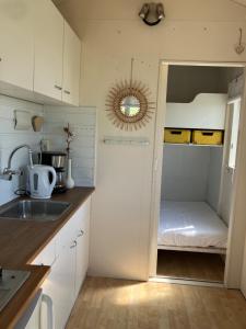 a kitchen with white cabinets and a sink and a mirror at Strandelijk plekje in Nieuwerkerk