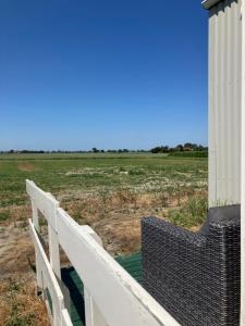 a white fence and a chair on a porch with a field at Strandelijk plekje in Nieuwerkerk +2 photos