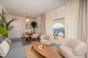 a living room with white furniture and a table and chairs at ILIOS COVE by A&D Properties in Porto Rafti