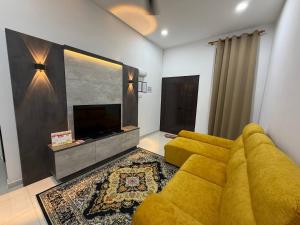 a living room with a yellow couch and a flat screen tv at Homestay Aydan at Kijal Kemaman in Cukai