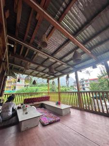 a person sitting on a porch with a bench on a deck at Boom Shankar in Kalgha