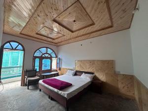 a bedroom with a large bed with a wooden ceiling at Boom Shankar in Kalgha