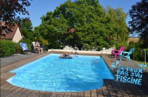 a swimming pool in a yard with two chairs and a table at La maison vautier in Vendeuvre-sur-Barse