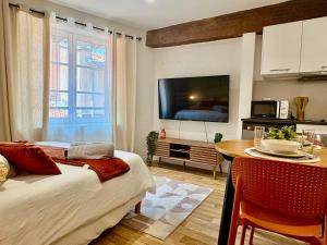 a room with a bed and a table and a tv at Le Cocon d'Or - Hyper centre - Clim - WIFI in Toulouse