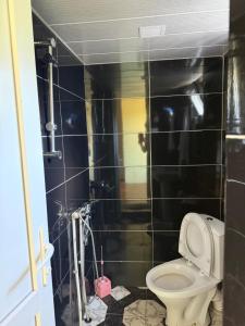 a bathroom with a toilet and a black tiled wall at Guesthouse Tetnuldi in Kʼolashi