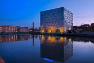 a building with a reflection in a body of water at Meliá Ria Hotel & Spa in Aveiro