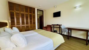 a hotel room with a bed and a table and a desk at Vila Ventura Village in Caniço