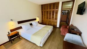 a bedroom with a large white bed and a chair at Vila Ventura Village in Caniço