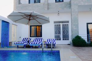 two chairs and an umbrella next to a swimming pool at Nile Kingdom Guest house in Luxor