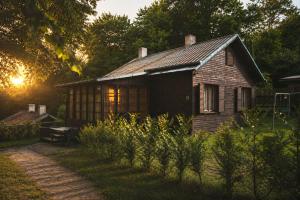 an old house in a garden with the sun setting at Kemp Selská rokle in Doksy