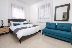 a bedroom with a bed and a blue couch at Villa Glory in Even Menahem +26 photos