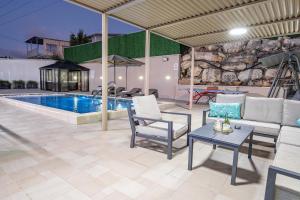 a patio with a couch and chairs and a pool at Villa Glory in Even Menahem