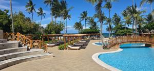 a resort swimming pool with a bridge and palm trees at JAZ Amaluna - Adults Friendly 16 Years Plus in Uroa