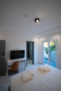 a white bedroom with a large bed and a television at Vivora Residence in Radovici
