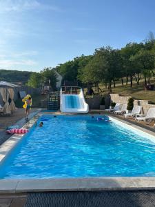 a person in a swimming pool with a pool slide at Trend Apartmanház -Vizslás in Vizslás