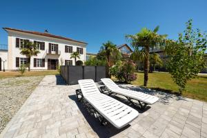 two white lounge chairs in front of a house at Corte Tegassa Pool & Spa in Pinerolo +90 photos