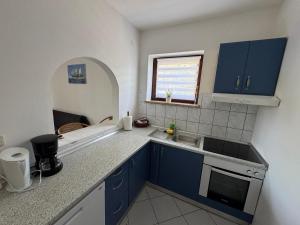 a small kitchen with blue cabinets and a window at Green House Villa with Pool in Banjole +22 photos