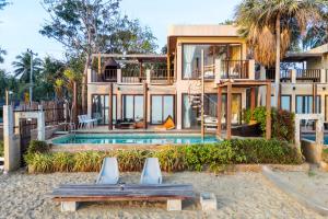 a house on the beach with a swimming pool at Cozy Beachfront Samroiyod in Baanphakrimlay 