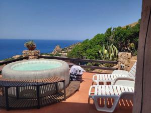 a patio with a hot tub and chairs and the ocean at Villa Sunny Side - Panoramic View in Costa Paradiso
