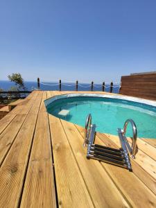 a swimming pool on a deck with a wooden table at Villa Sunny Side - Panoramic View in Costa Paradiso