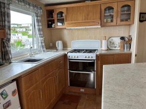 a kitchen with a stove and a sink at Beer Head Caravan Park B68 in Seaton