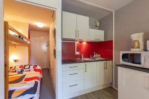 a small kitchen with white cabinets and a microwave at La Mongie Parking Petfriendly in Bagnères-de-Bigorre