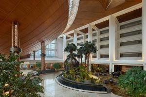 a large lobby with palm trees in a building at Gran Meliá Jakarta in Jakarta
