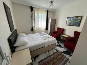 a small bedroom with a bed and two red chairs at BEYAZEV Apart in Erdek