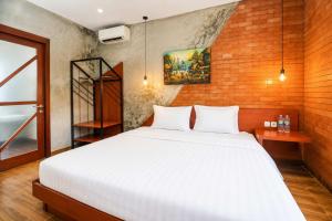 a bedroom with a white bed and a brick wall at Noesa Heritage in Surabaya