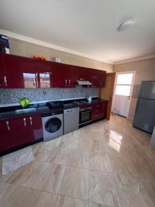 a kitchen with red cabinets and a washer and dryer at Apartment Selouane in Selouane