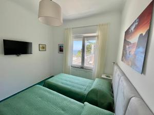 a room with two green beds and a window at La Marilena Penthouse in Capri