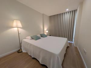 a bedroom with a white bed and a lamp at Coração dos Arcos in Arcos de Valdevez