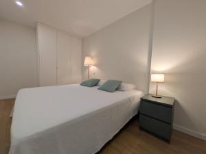 a bedroom with a large white bed and two lamps at Coração dos Arcos in Arcos de Valdevez +3 photos