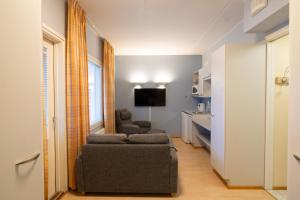 a living room with two chairs and a couch and a television at Spa Hotel Rauhalahti in Kuopio