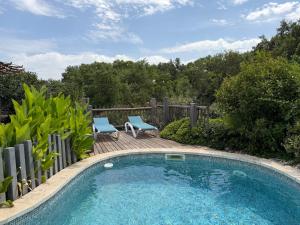 a small swimming pool with two blue chairs next to a fence at L'arbousier in Clermont-lʼHérault