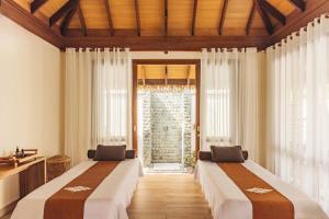 two beds in a room with a window at Meliá Whale Lagoon Maldivas in Fenfushi