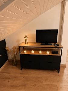 a entertainment center with a television and candles on it at Le Petit Loft Vosgien -Escapade nature & cosy in Cornimont
