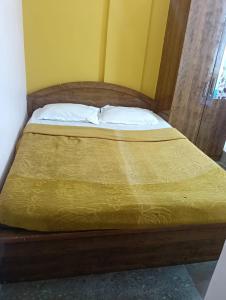 a bed with a wooden frame with two pillows on it at Sri Sapthagiri Comforts in Mysore