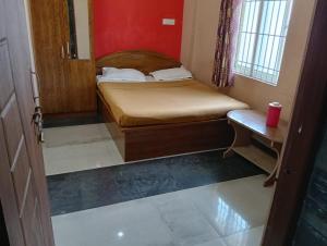 a small bedroom with a bed and a table at Sri Sapthagiri Comforts in Mysore