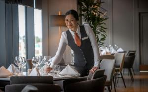 a woman is standing at a table in a restaurant at Clayton Hotel Leopardstown in Leopardstown