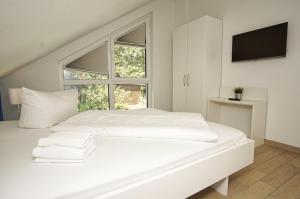 a white bedroom with a white bed and a window at Ferienhaus am Dünenstrand in Baabe
