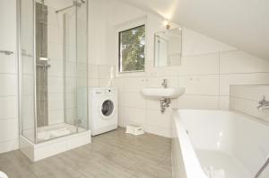 a white bathroom with a washing machine and a sink at Ferienhaus am Dünenstrand in Baabe +30 photos