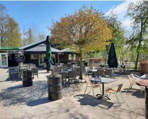 a patio with tables and chairs and umbrellas at Chalet Feanzicht in Earnewâld