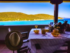 a table with wine glasses on it with a view of the ocean at Tholos Alexandra's Beachfront House in Kavoúsion