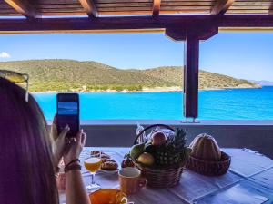 a woman taking a picture of a table with a view of the ocean at Tholos Alexandra's Beachfront House in Kavoúsion +38 photos