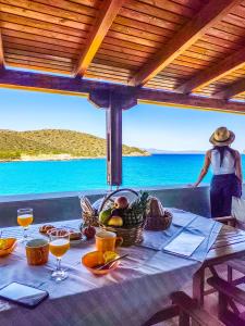 a table with a basket of fruit and a person in the ocean at Tholos Alexandra's Beachfront House in Kavoúsion