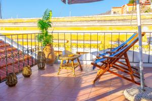 a balcony with a ladder and a chair on a roof at Kali Strata 2 - Downtown in Symi